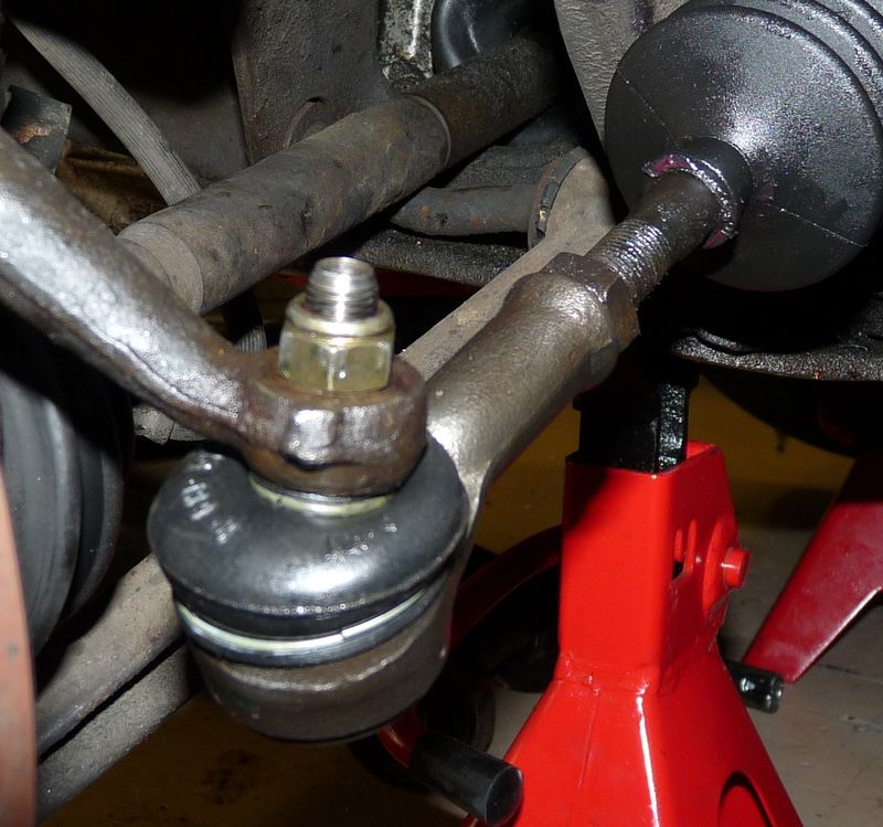 Tie rod end with castle nut on a steering knuckle, seen under a car